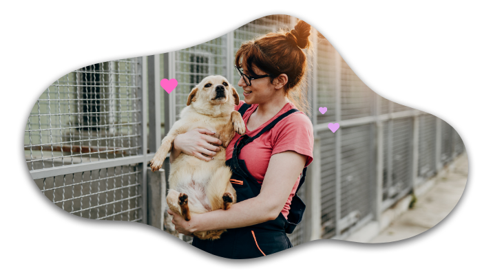 Woman in red shirt and overalls holding a smiling dog near a fenced area, with pink hearts floating around.